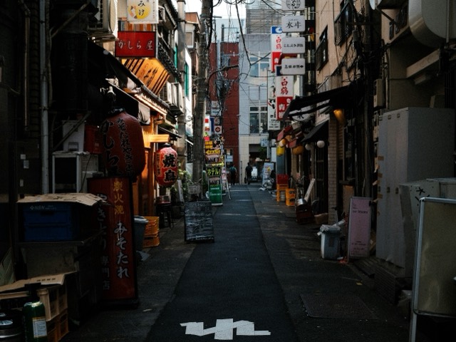 A narrow Asian city street filled with signs and balconies