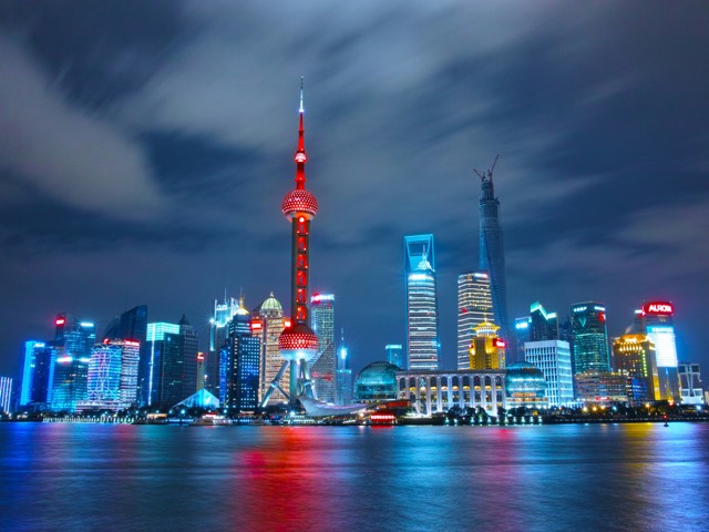 Shanghai skyline glowing across the Huangpu River at night